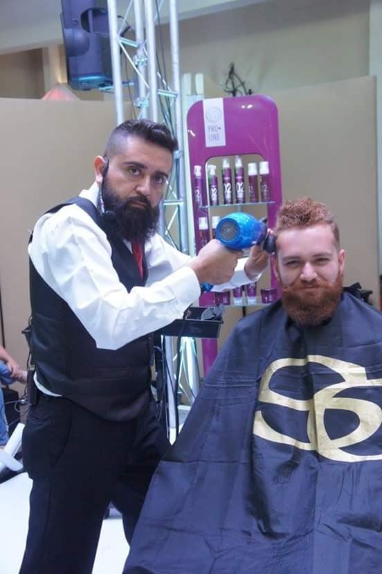 Barbero con chaleco y camisa blanca cortando el pelo a un cliente en una barbería