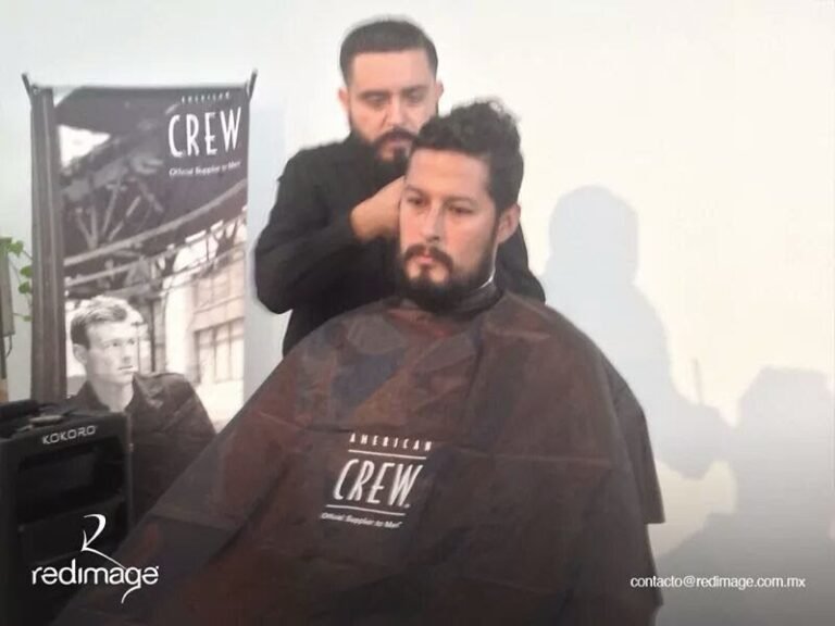 Barbero cortando el pelo a un cliente con una capa de American Crew