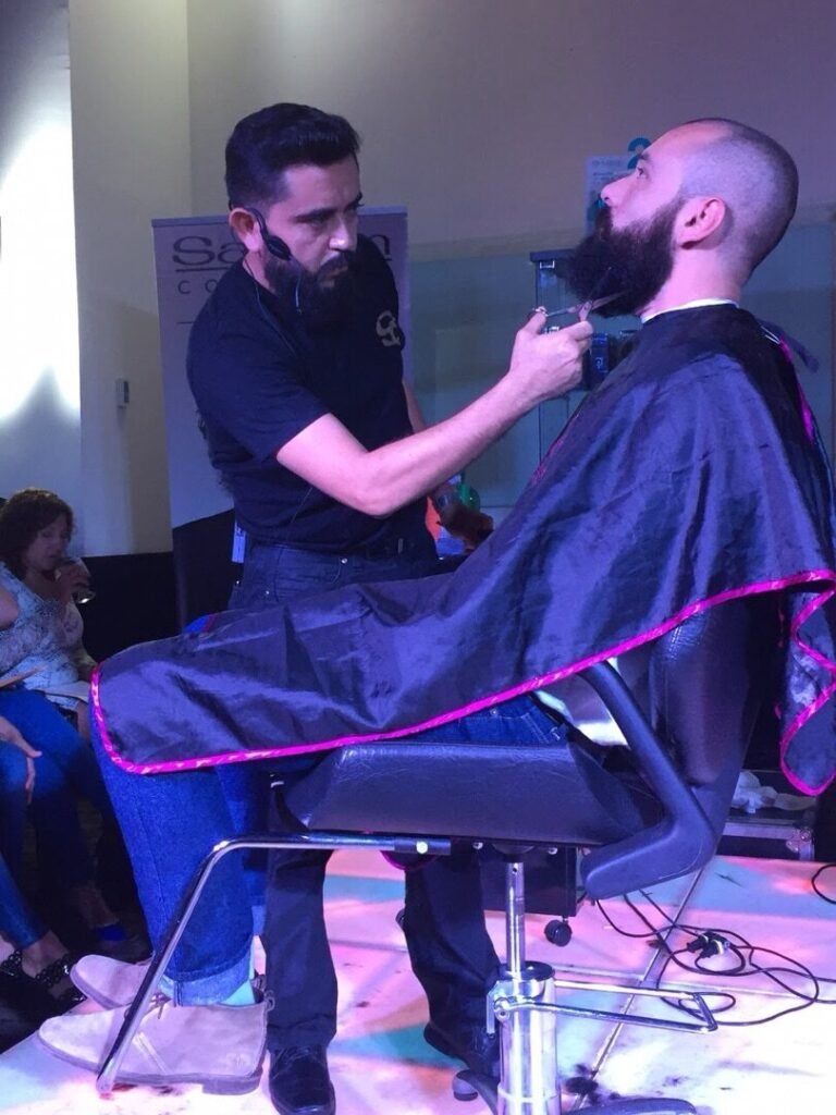 Barbero cortando el pelo a un cliente sentado en un sillón, con otra persona al fondo