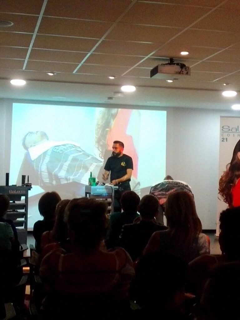 Demostración de barbería ante un público con una pantalla de proyección al frente